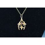 An Edwardian rose gold and ruby pendant in the form of a horseshoe entwined with flowers and leaves,