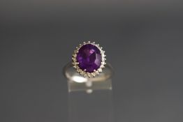 An 18ct white gold, amethyst and diamond oval cluster ring,