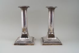 A pair of silver column candlesticks, each with a plain nozzle,