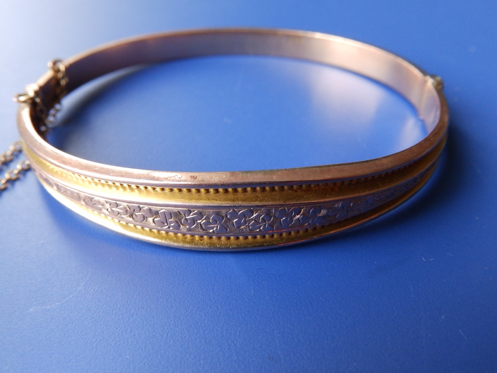 A 9ct gold bangle with engraved decoration.