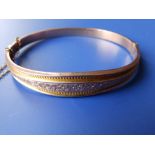 A 9ct gold bangle with engraved decoration.