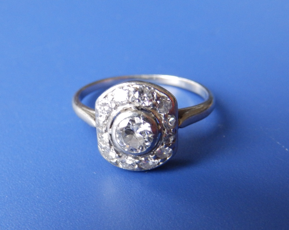 An art deco diamond set white metal panel cluster ring, the central brilliant weighing approximately