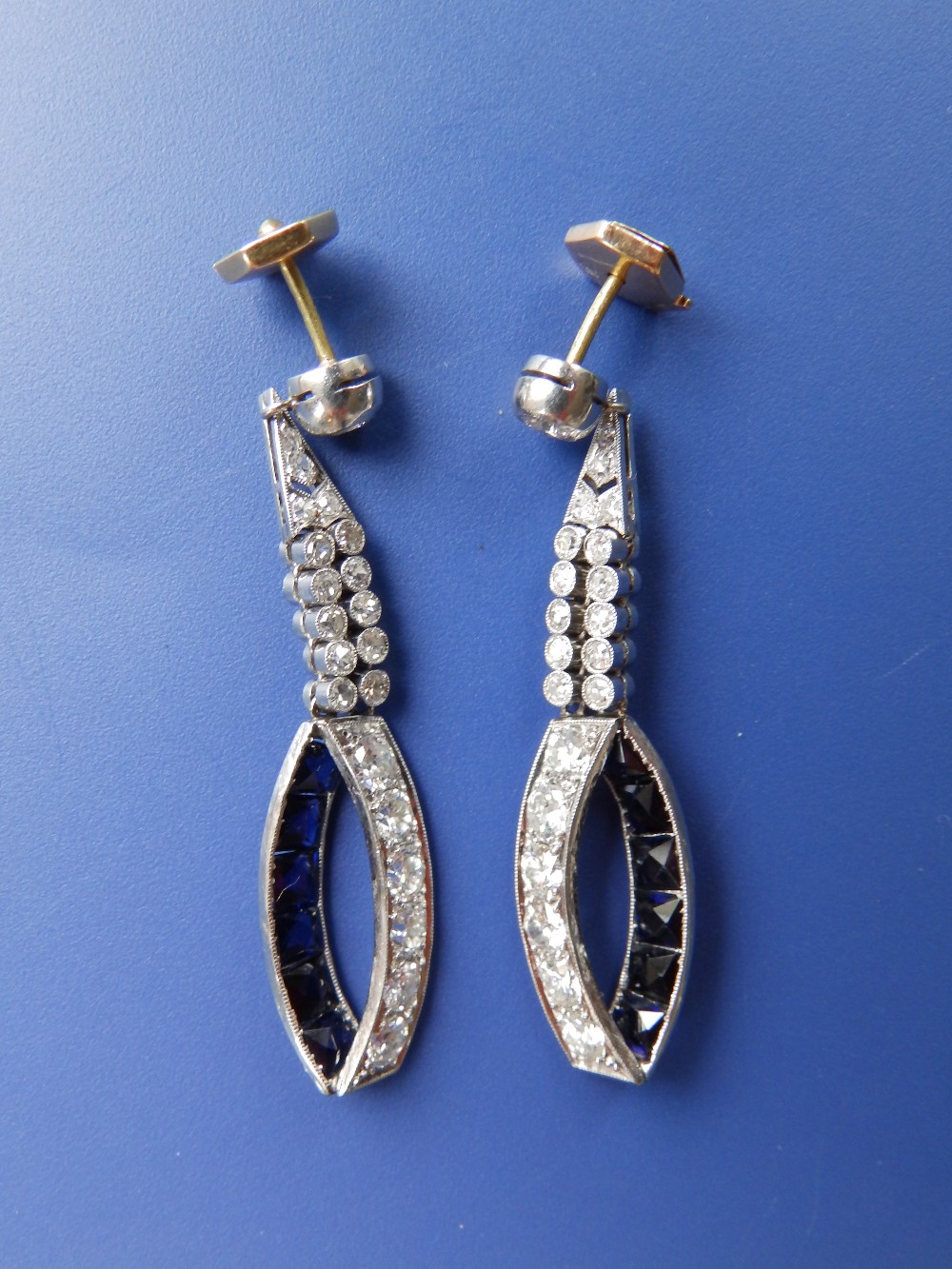 A pair of diamond & sapphire set white metal drop earrings, each having numerous millegrain set