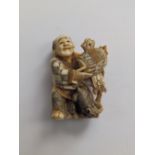 A Japanese signed ivory netsuke depicting a man holding a mallet with a rat at his feet, 1.75”