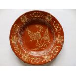 An old slip glazed red earthenware plate, decorated with a bird and a tree, 8.75”