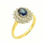 An 18 ct gold oval sapphire and double diamond cluster ring, size W (see illustration).