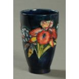 A Moorcroft beaker, with blue ground and floral sprays, impressed "Moorcroft, Made in England".