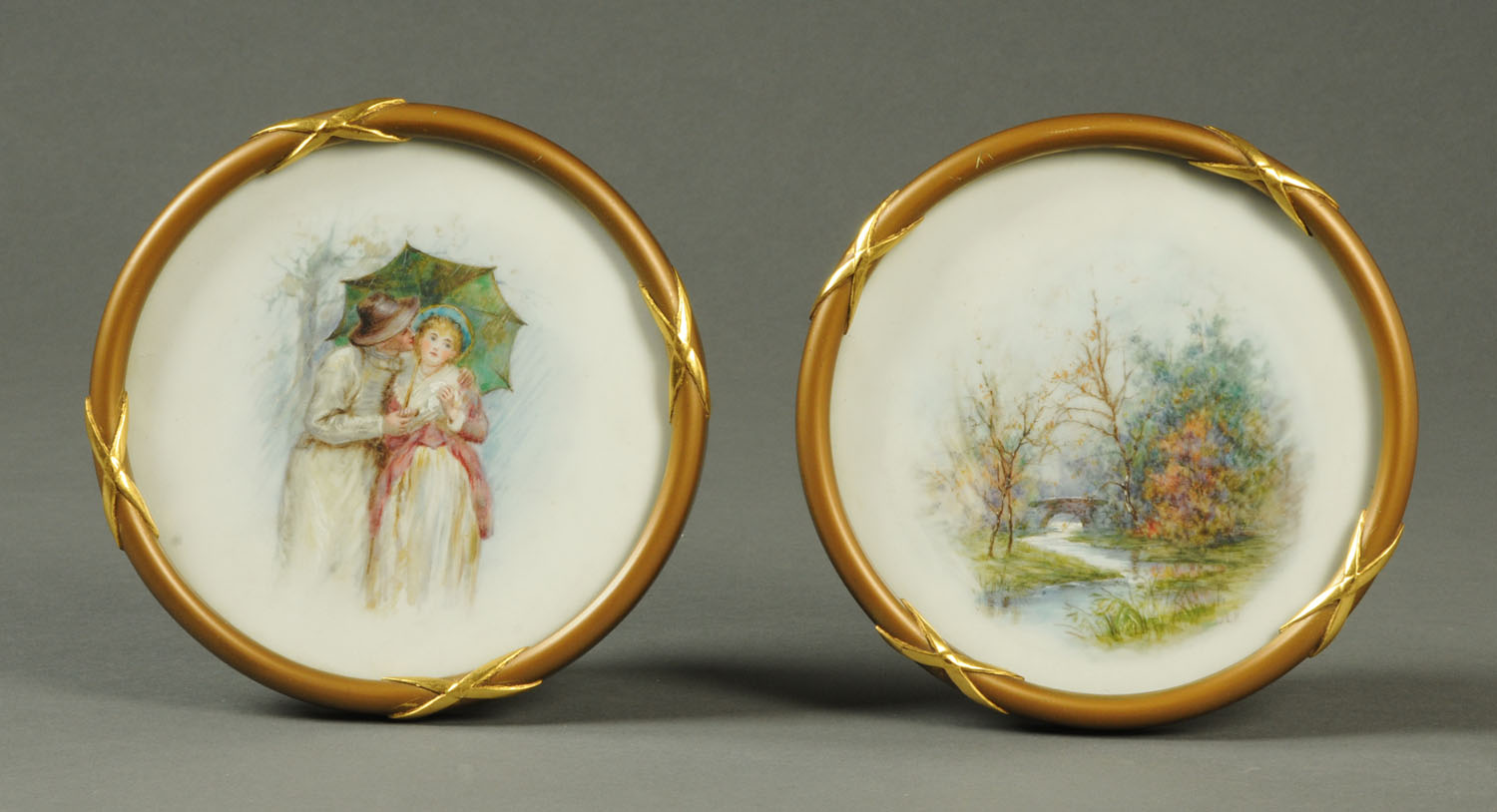 A pair of handpainted porcelain plaques, circular, each in gilt frame and glazed,