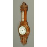 An aneroid barometer, with carved oak case and with thermometer. Height 65 cm.