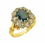 An 18 ct yellow and white gold claw set sapphire and diamond ring, the oval sapphire +/- 1.