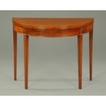 A George III mahogany demi-lune turnover top tea table, raised on tapered legs of square section.