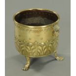 A large brass jardiniere, embossed, with carrying handle to either side and raised on paw feet.