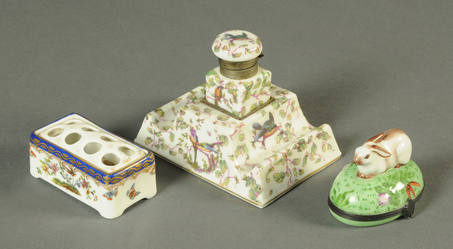 A 19th century porcelain inkwell on stepped stand, a Continental pen stand and a trinket box.