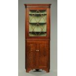 A late Georgian oak and mahogany corner cupboard, with wooden astragals to the upper half.