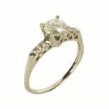 A solitaire diamond ring, with two diamonds to each shoulder, white coloured metal shank,