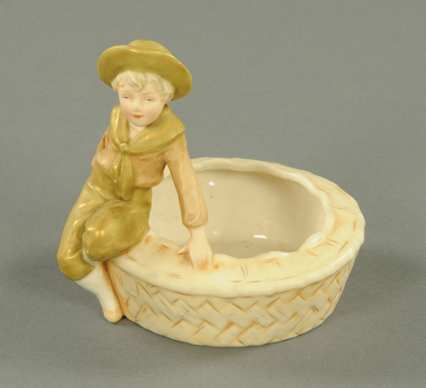 A Royal Dux figure, seated boy, pink triangular mark to base. Diameter 12 cm.