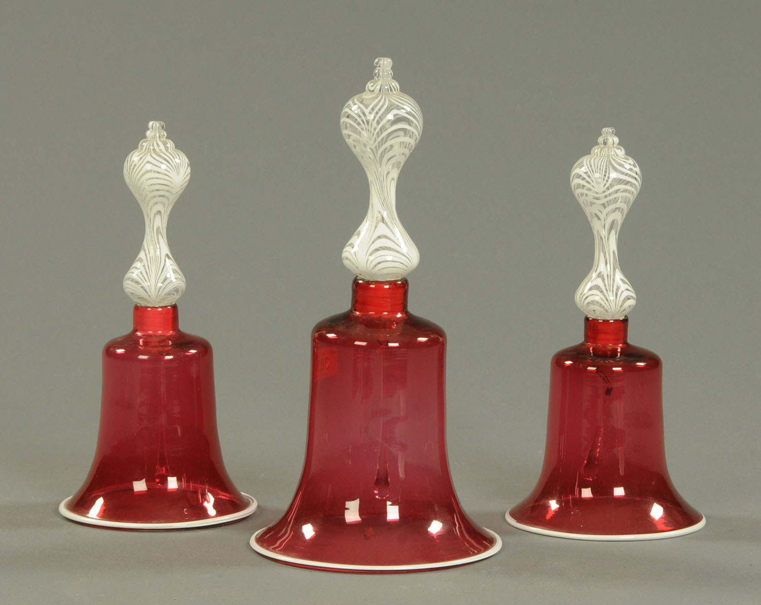 A set of three 19th century cranberry and milk glass bells. Tallest 35 cm.