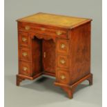 A George III style inlaid walnut kneehole desk, with green tooled leather writing surface,