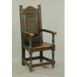 A late Victorian oak throne armchair, with carved panel back, solid seat,
