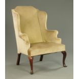 An early 18th century wing easy chair, raised on front cabriole legs and rear chamfered angled legs.