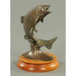 A bronze model of a leaping salmon, raised on a wooden base. Overall height 25 cm.