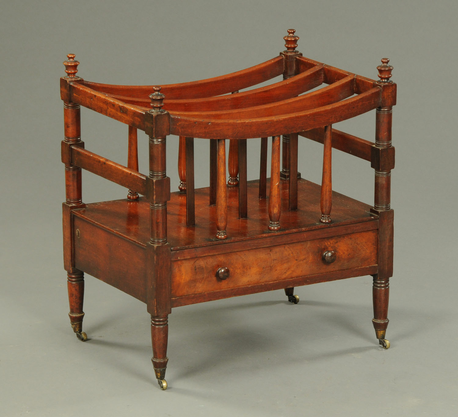 An early 19th century mahogany Canterbury, three divisions, with turned columns,