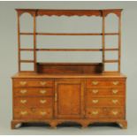A George III oak dresser with Delft rack, with moulded cornice above a series of open shelves,
