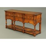 A George III style oak and mahogany crossbanded dresser base, with three drawers,