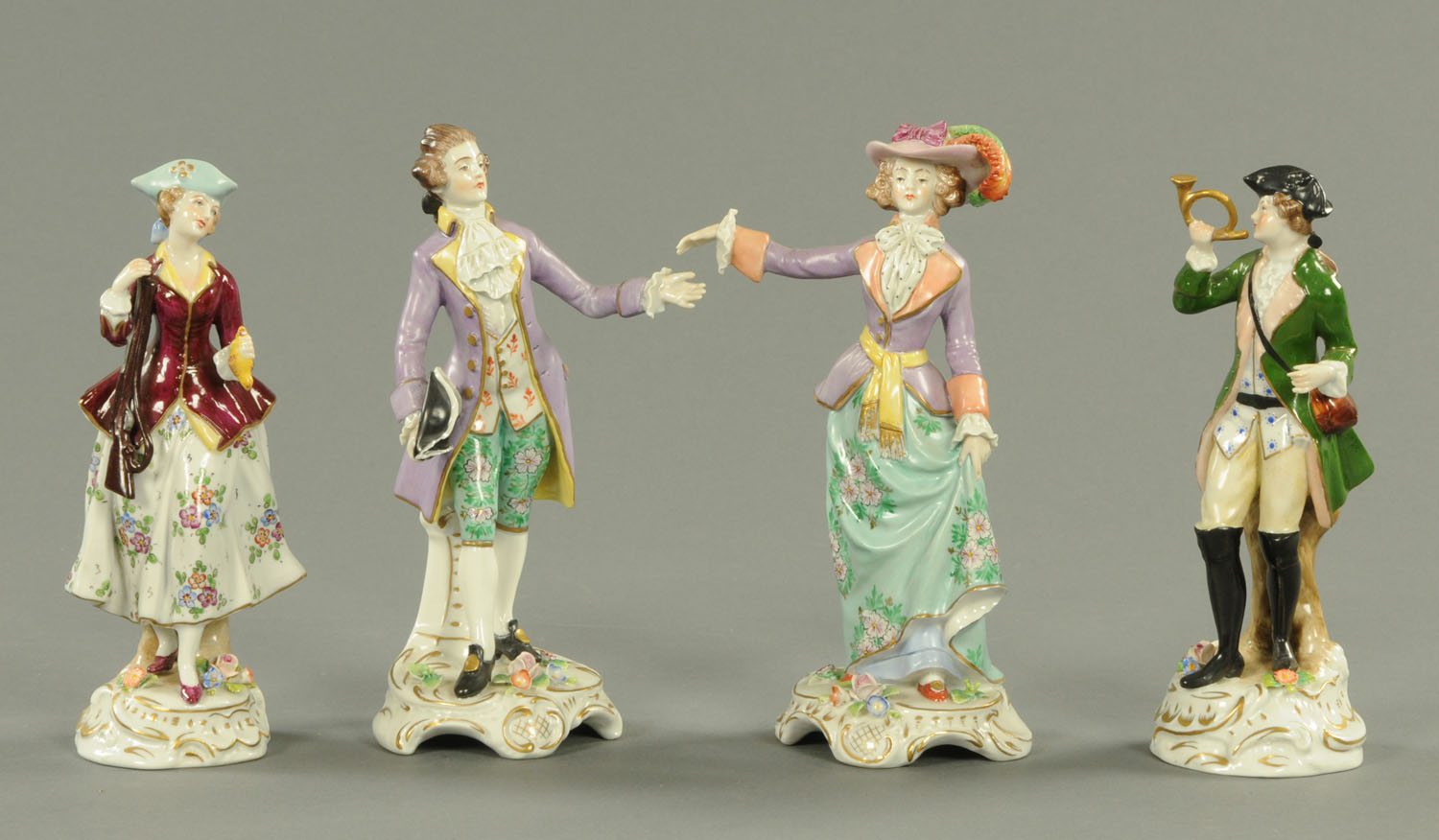 Four Continental porcelain figurines, each with floral encrusted bases. Height 19 cm.