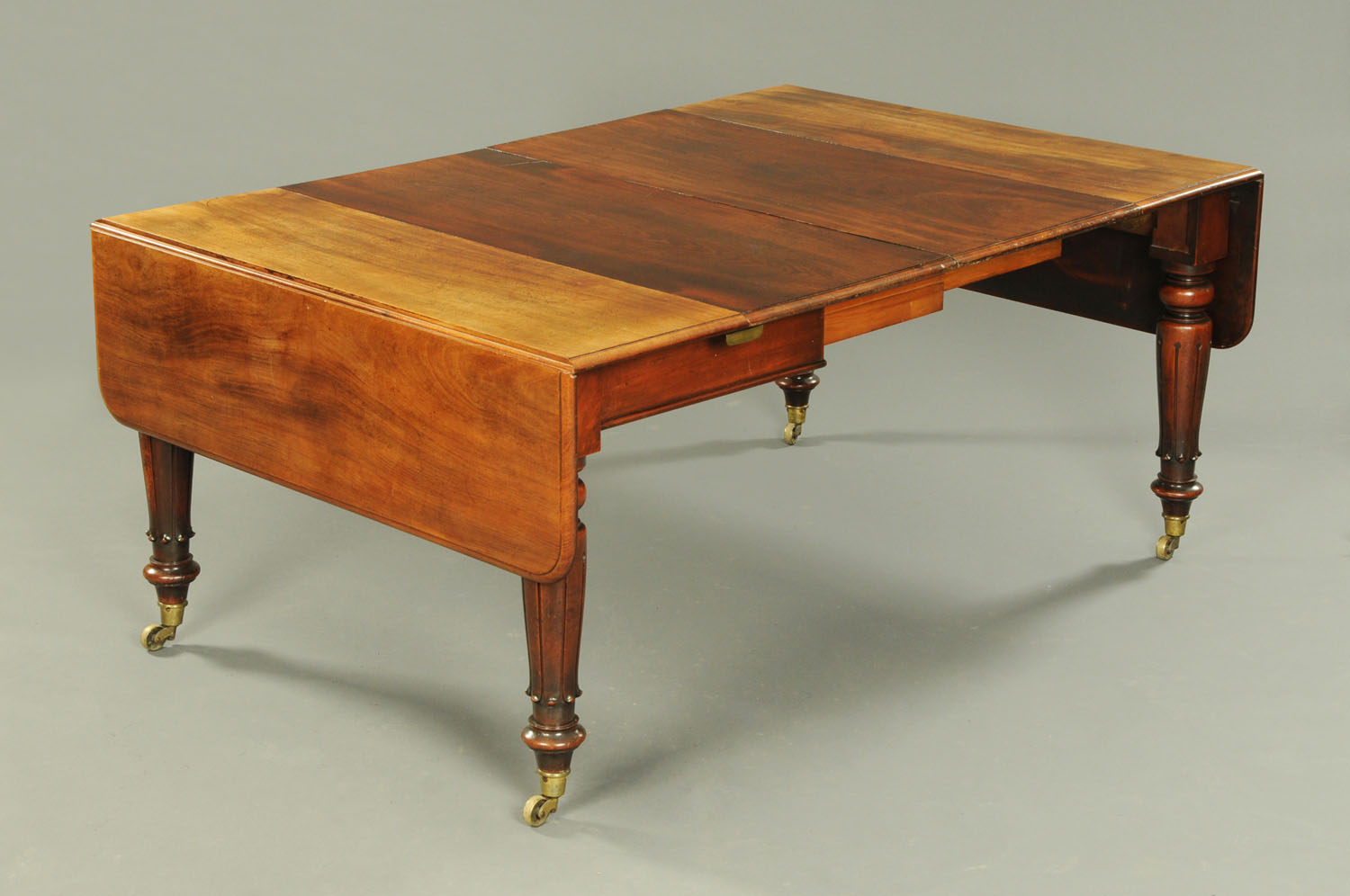 A Victorian mahogany twin drop flap dining table with two centre leaves,