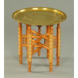 An Islamic brass topped folding table, with wooden base. Diameter 52.5 cm.