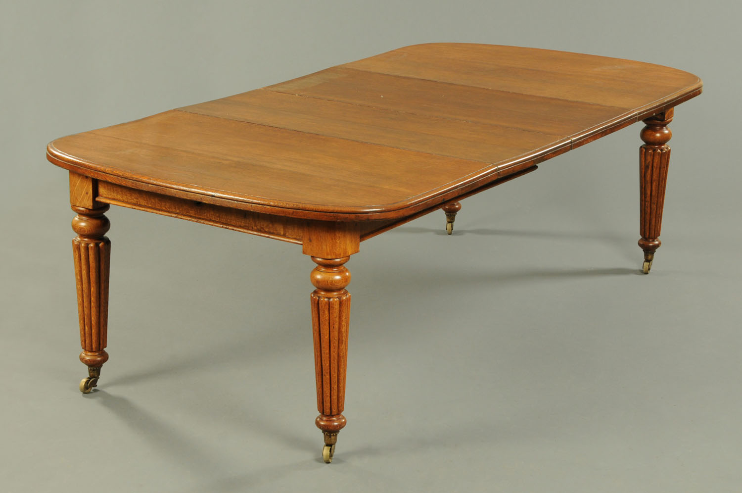 A Victorian oak extending dining table, with two leaves,