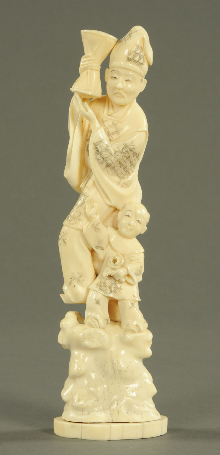 A Chinese ivory figure group, man with drum and boy, circa 1900. Height 26 cm.
