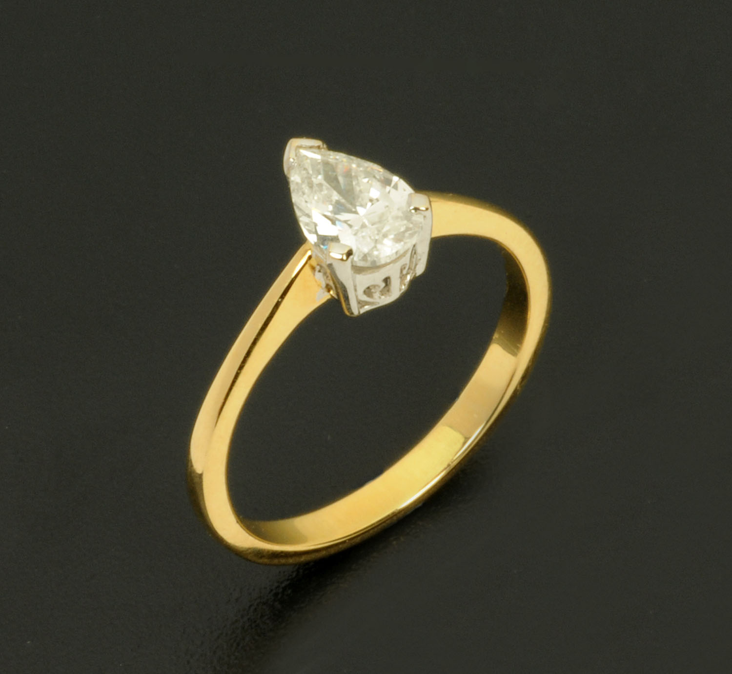 An 18 ct two tone gold solitaire diamond ring, pear shaped, weighing +/- .72 carats, size L/M.