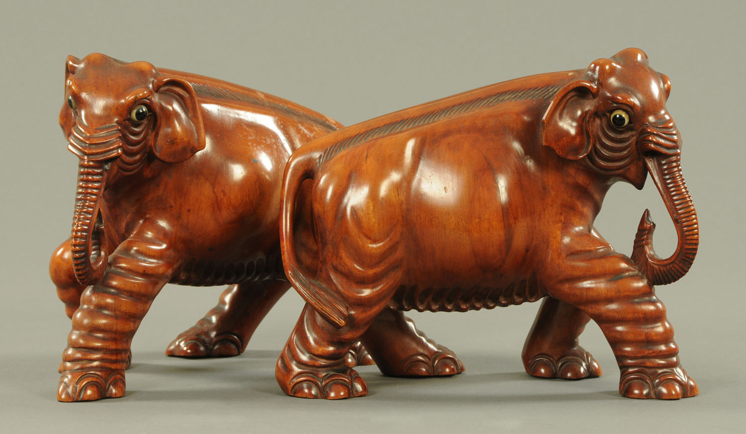 A pair of carved wood Indian elephants, early 20th century, each with inset glass eyes. Height 18.