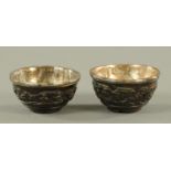A pair of carved Chinese coconut tea bowls, early 18th century, carved in relief with figures,