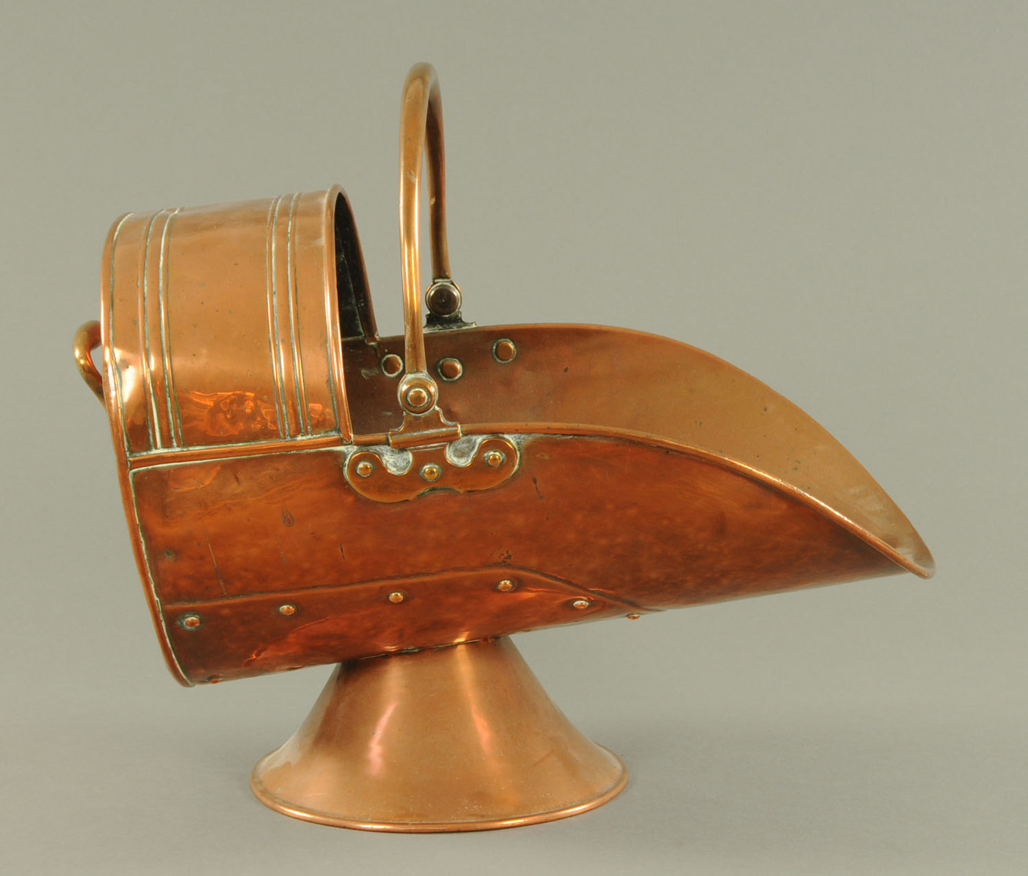 A copper coal scuttle, 19th century, with bale handle and supported upon a circular foot.