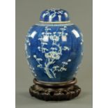 A Chinese blue and white prunus pattern jar and cover, late Qing, upon a carved hardwood stand.