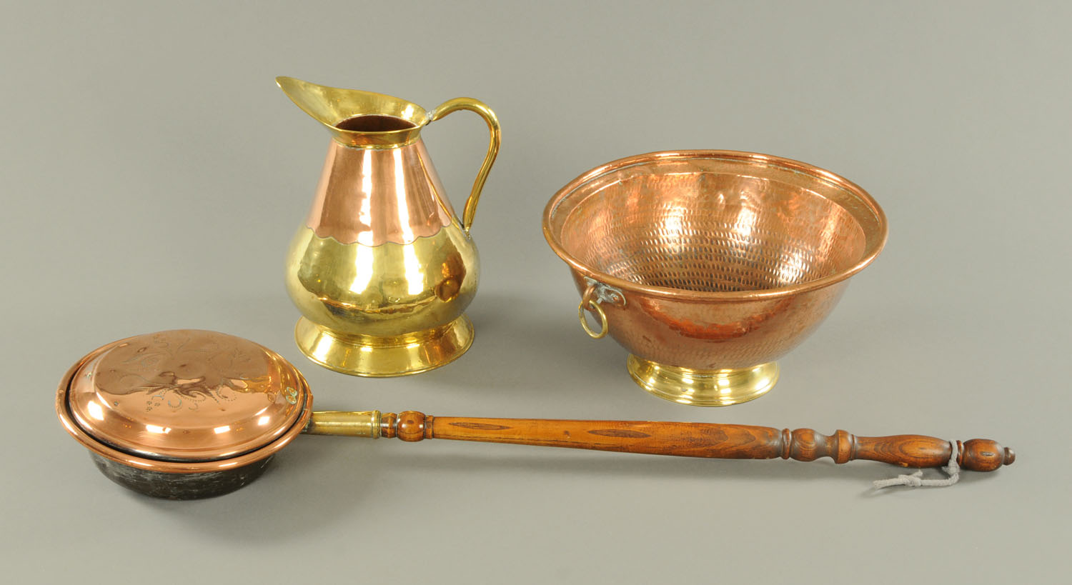 A copper and brass water jug, Eastern copper bowl with brass foot and ring handles,