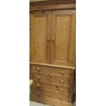 A 20th Century pine cupboard on a chest of four drawers to plinth base