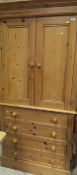 A 20th Century pine cupboard on a chest of four drawers to plinth base