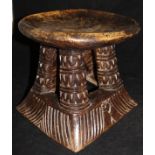 An early 20th Century African tribal stool on four carved splayed supports to carved base