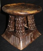 An early 20th Century African tribal stool on four carved splayed supports to carved base