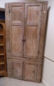 A Victorian bleached pine corner cupboard with two panel doors above two short doors