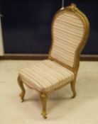A Victorian nursing chair with painted frame and cream striped upholstered seat and back to
