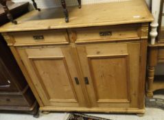 A pine cupboard with two short drawers above two cupboard doors enclosing shelves together with a