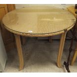 A wicker top circular dining table with faux bamboo legs