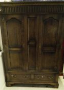 A 20th Century oak two door wardrobe with dentil carved corners above two panel doors above two