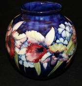 A Moorcroft vase decorated with iris and other flowers on a deep blue ground,