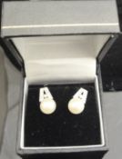 A pair of 14 carat white gold diamond and pearl set ear studs in the Art Deco taste